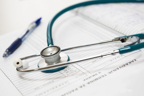 Closeup photo of blue stethoscope on white printed paper copy