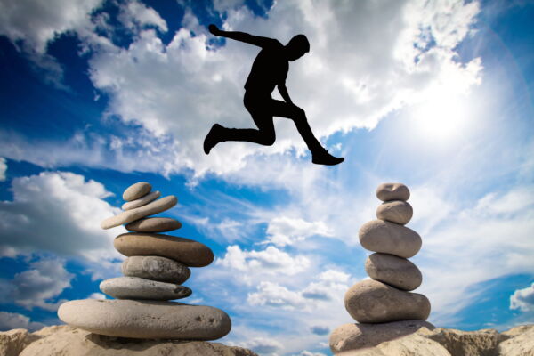 Man jumping above balance stones photo free download