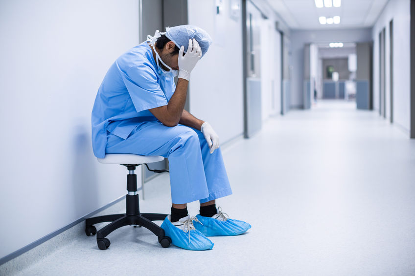 Sad surgeon sitting on a chair in hospital corridor